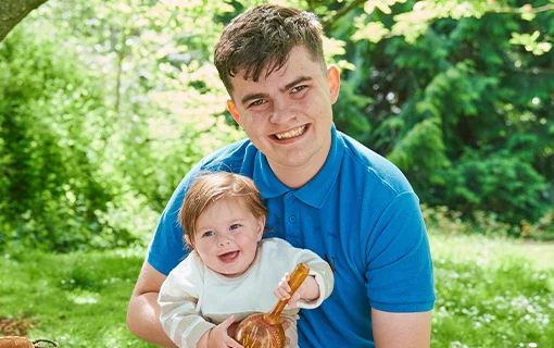 a male Norland student holding a smiling baby