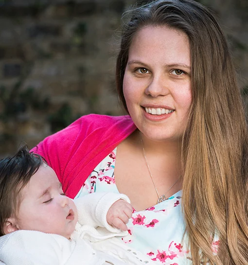 Nanny Sophie holding a baby smiling to camera