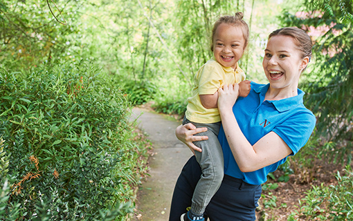 A Norland Nanny student holding a boy, both smiling