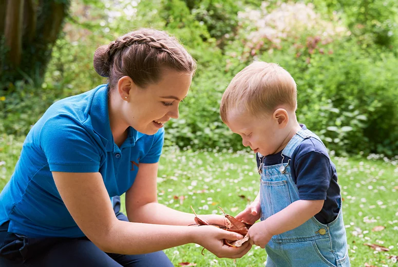 A Norland student and a toddler with leaves in their hands