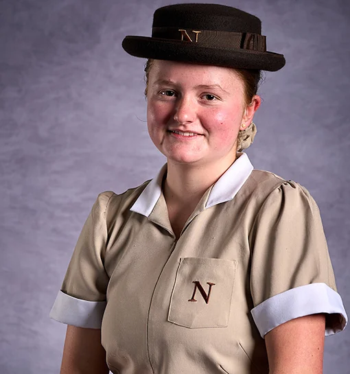 Norland student in formal uniform smiling in studio background