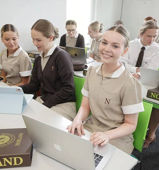 A Norland student sat at a desk with a laptop in front of her smiling