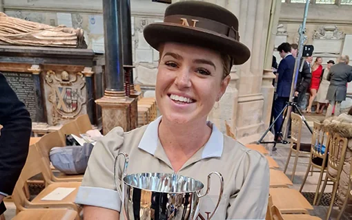 A fully qualified Norland Nanny holding a trophy at her graduation at Bath Abbey, Bath