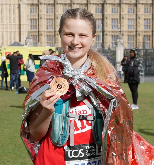 A female outside Big Ben, London holding a London Marathon medal