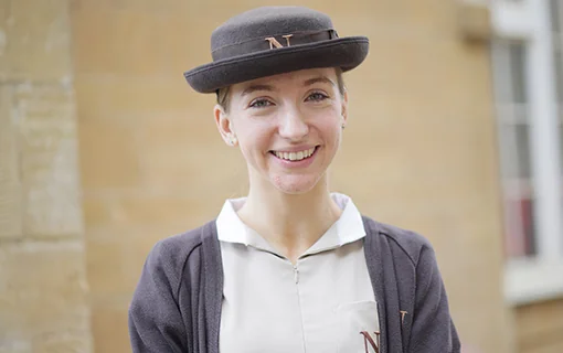 Student in formal uniform and hat smiling headshot